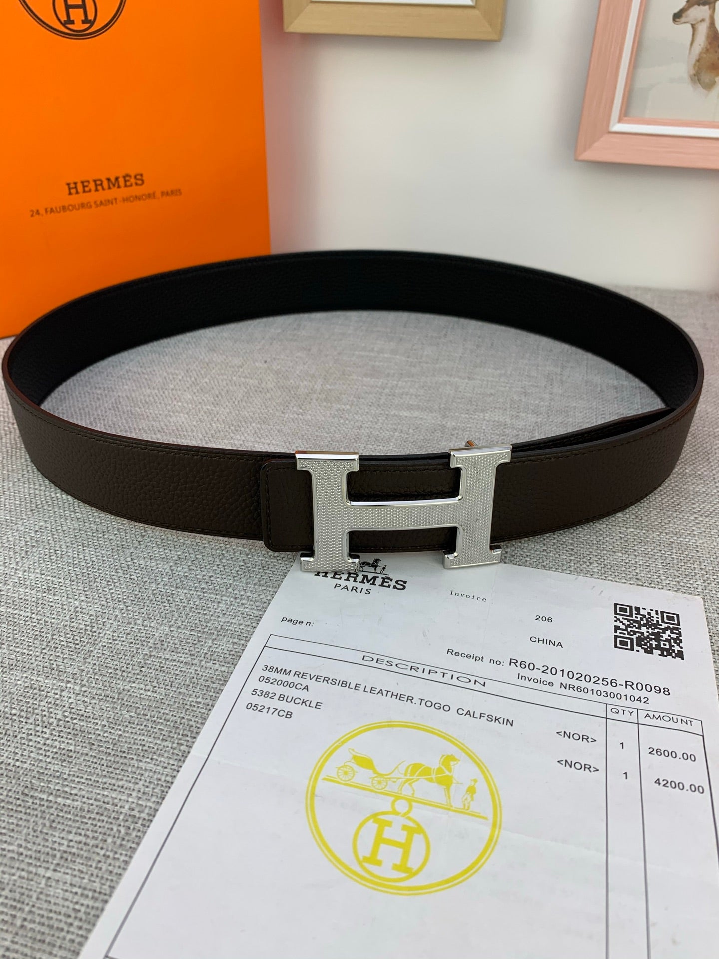 Dark leather belt with silver-tone H buckle across the front