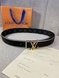 Black monogram belt with gold-tone square buckle, laid on receipt and box