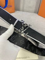 Black monogram belt close-up with silver-toned keeper and gold square buckle