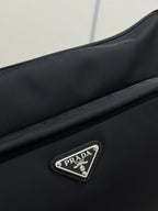 Prada dark bag front close-up with textured leather and silver logo plaque