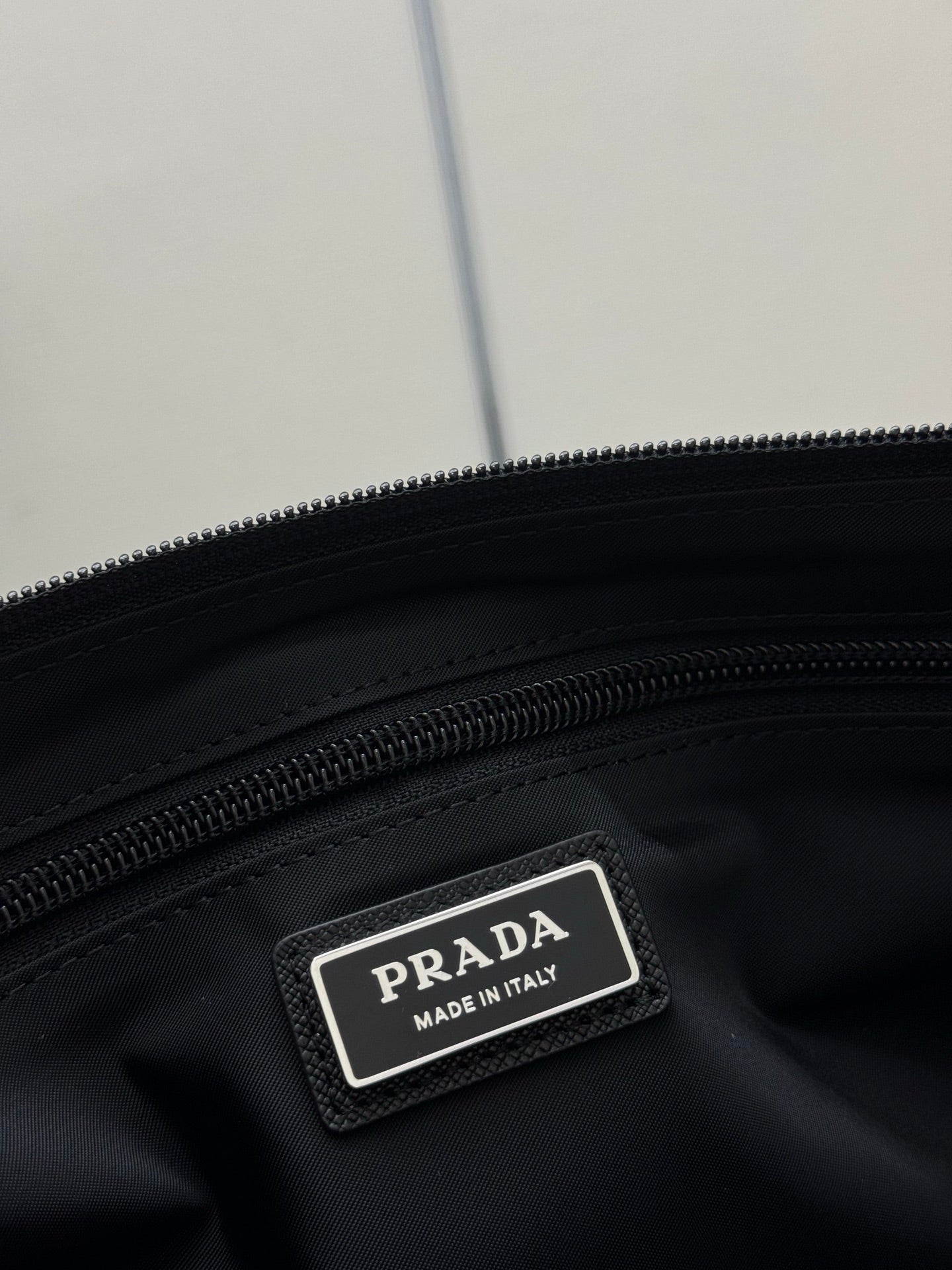 Prada dark bag label patch reading “PRADA” and “MADE IN ITALY”