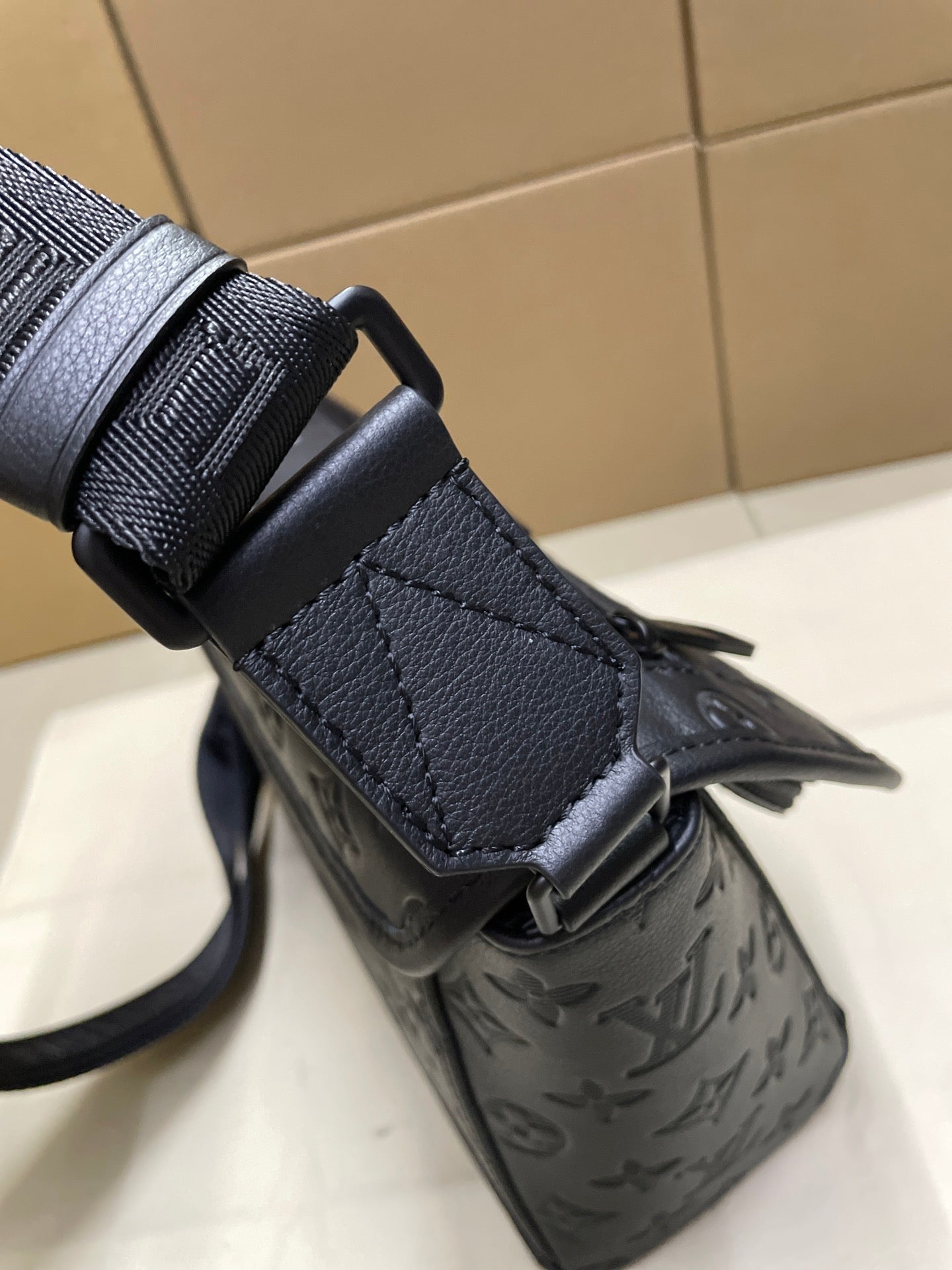 Men's Louis Vuitton monogram bag close-up, dark navy strap attachment and textured exterior