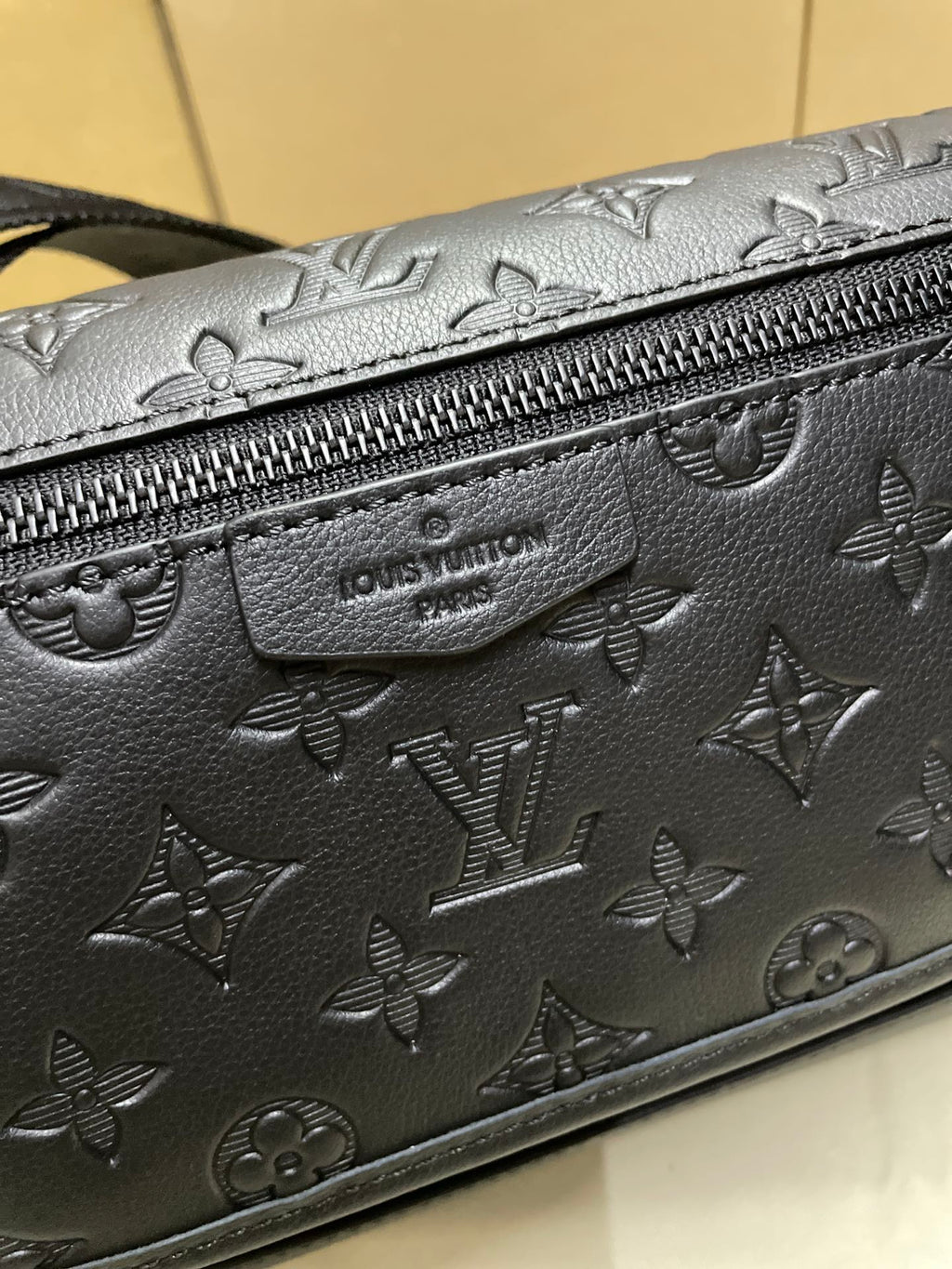 Louis Vuitton dark monogram crossbody bag close-up of embossed pattern and zipper pull