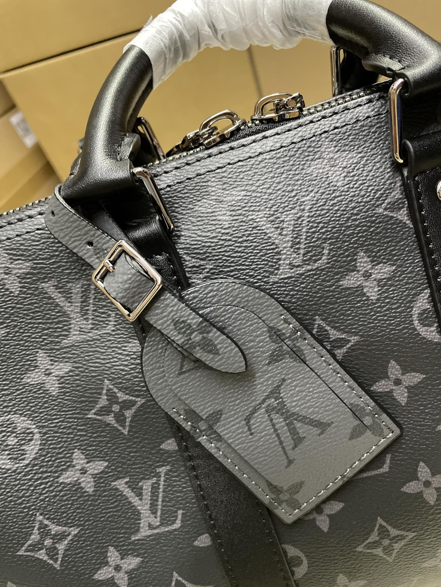 Monogram handbag close-up with textured leather, front clasp, and luggage tag