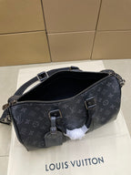 Monogram crossbody bag with open top, zipper pull, and front buckle detail