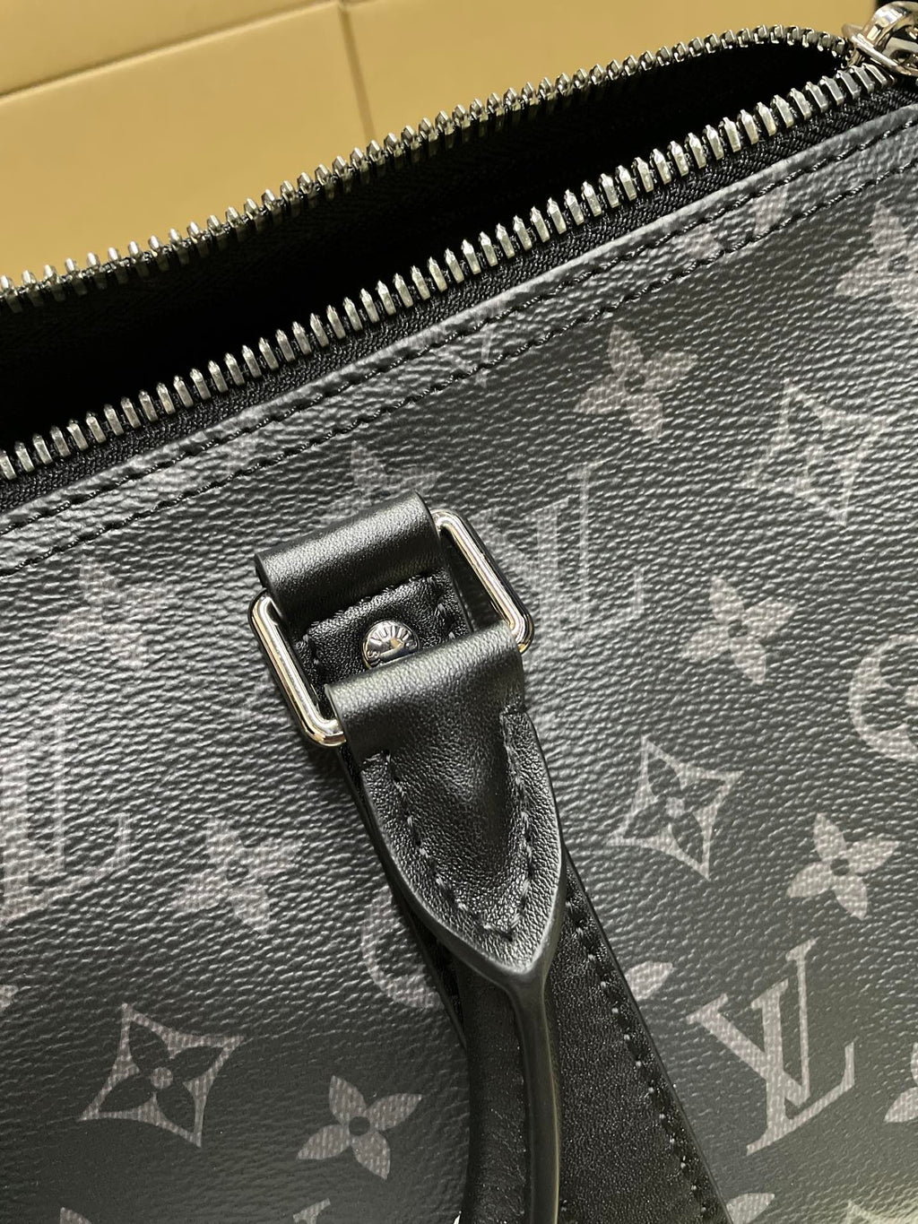Louis Vuitton monogram bag close-up of zipper pull and metal hardware, dark gray