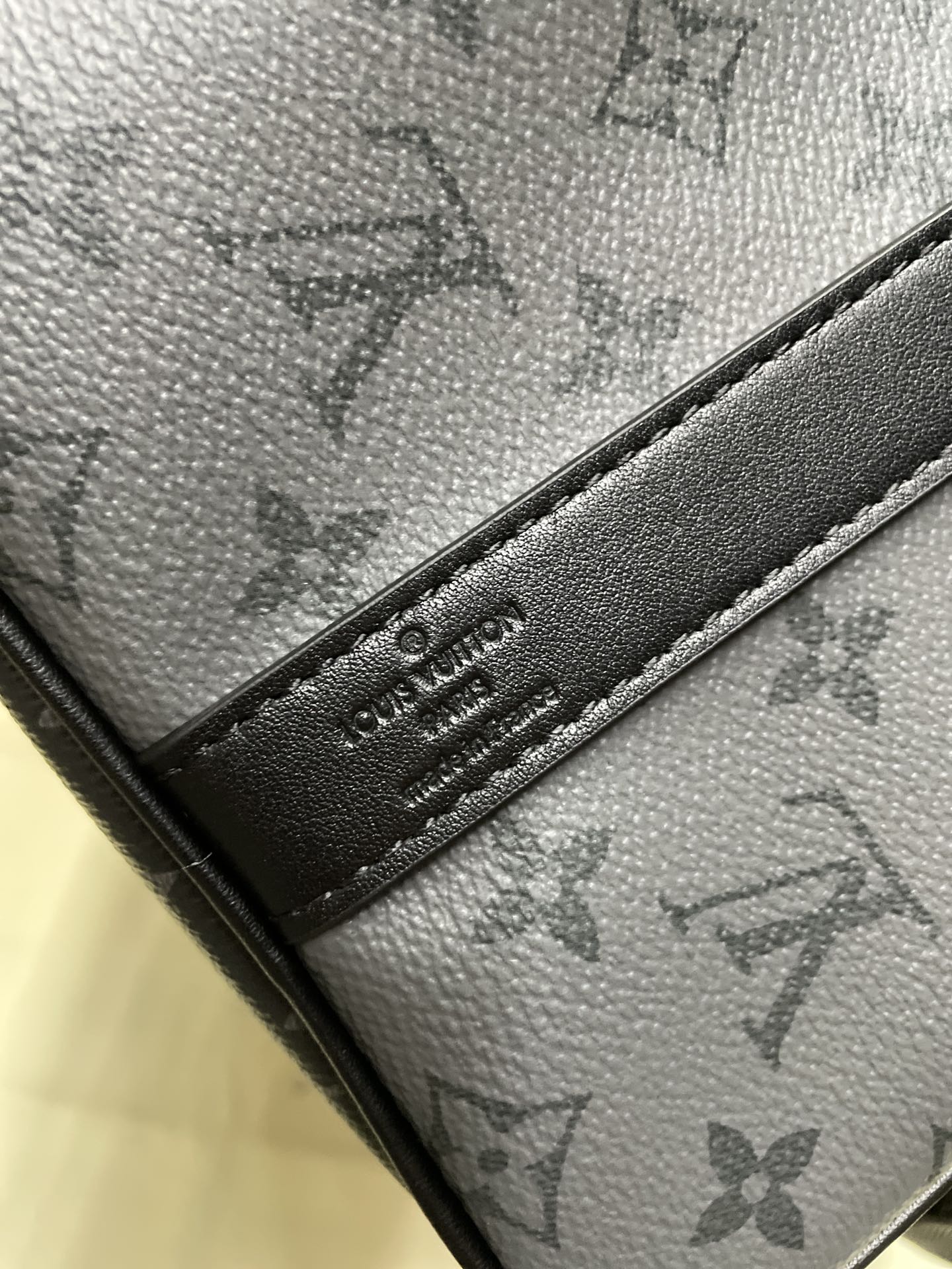 Louis Vuitton monogram bag close-up of leather label on dark tab, dark gray