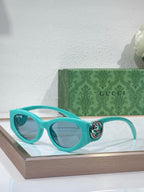 Gucci sunglasses with teal frame and light blue lenses, round logo hinge