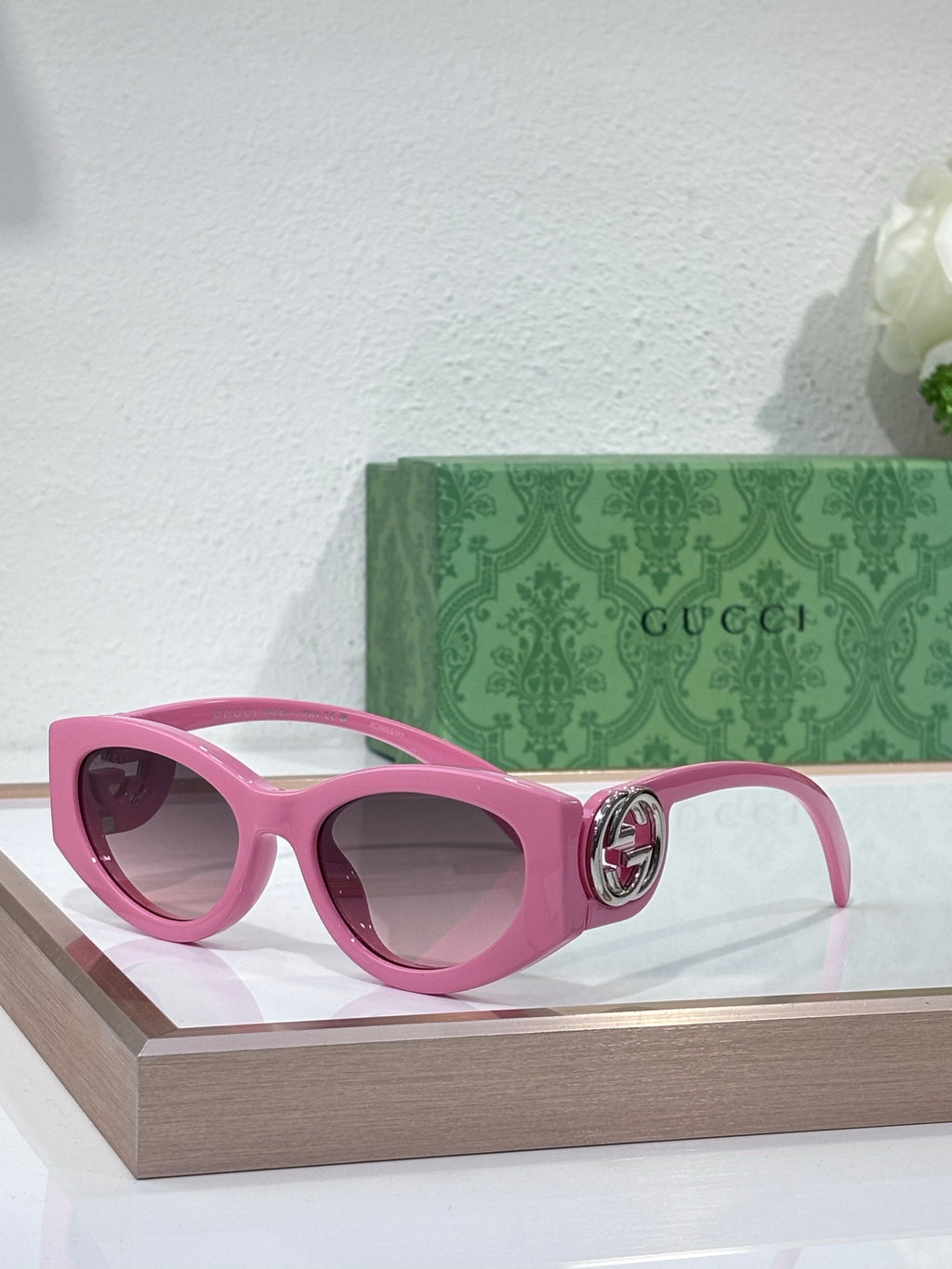 Gucci sunglasses with pink frame and dark lenses, ornate hinge emblem