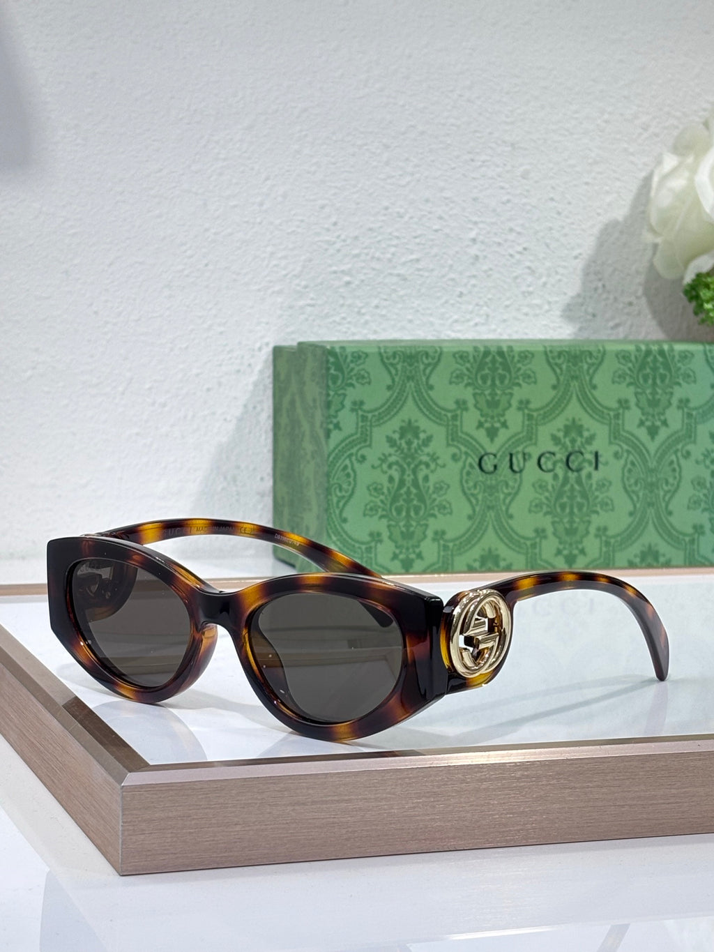 Gucci sunglasses with tortoiseshell frame and dark lenses, round logo hinge