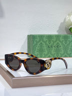 Gucci sunglasses with tortoiseshell frame and dark lenses, round logo hinge