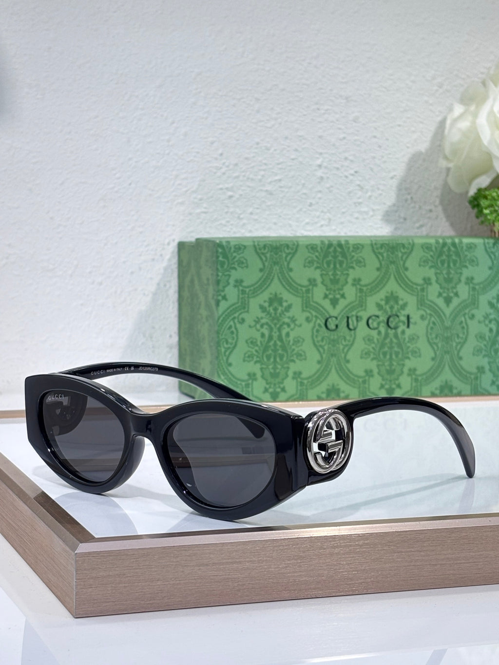 Gucci sunglasses with black frame and dark lenses on a display stand