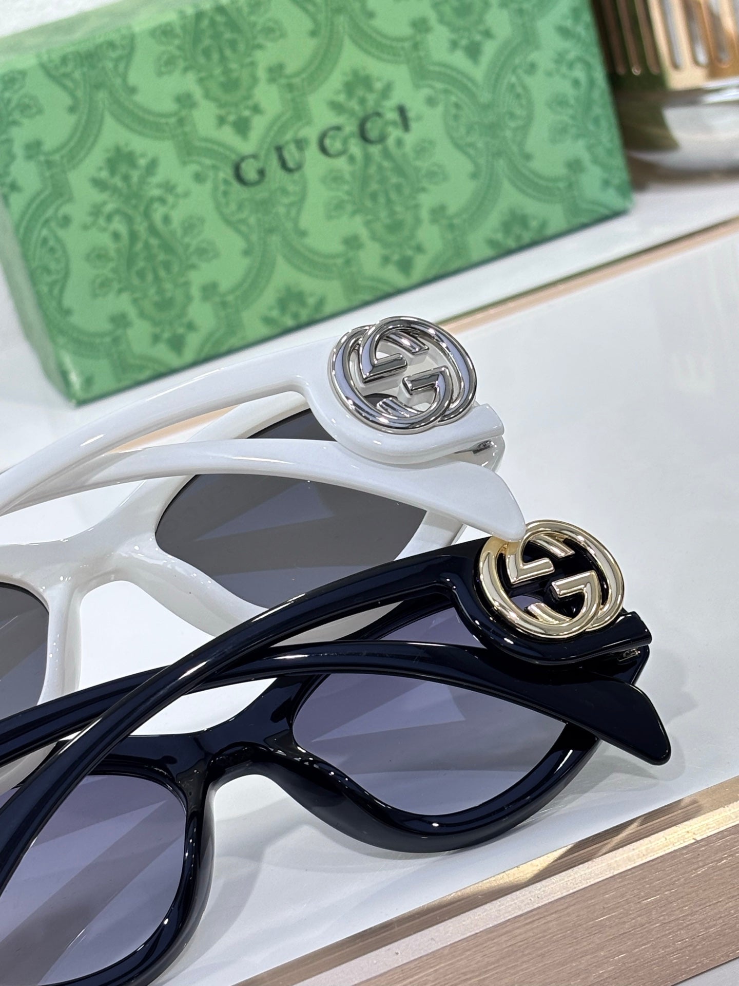 Gucci sunglasses detail: white frames with dark blue temples and metal logo hinge