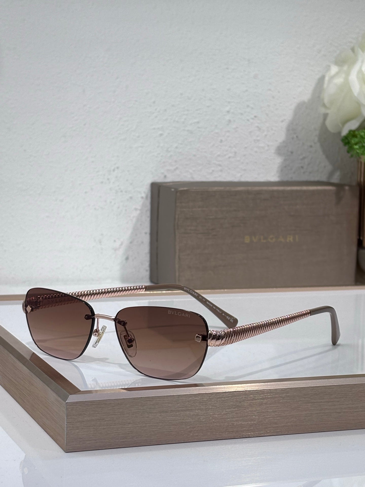 Metal-framed oval sunglasses with brown lenses and gold textured temple arms