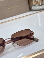 Brown-lensed oval sunglasses with metal frame and textured gold temple detail
