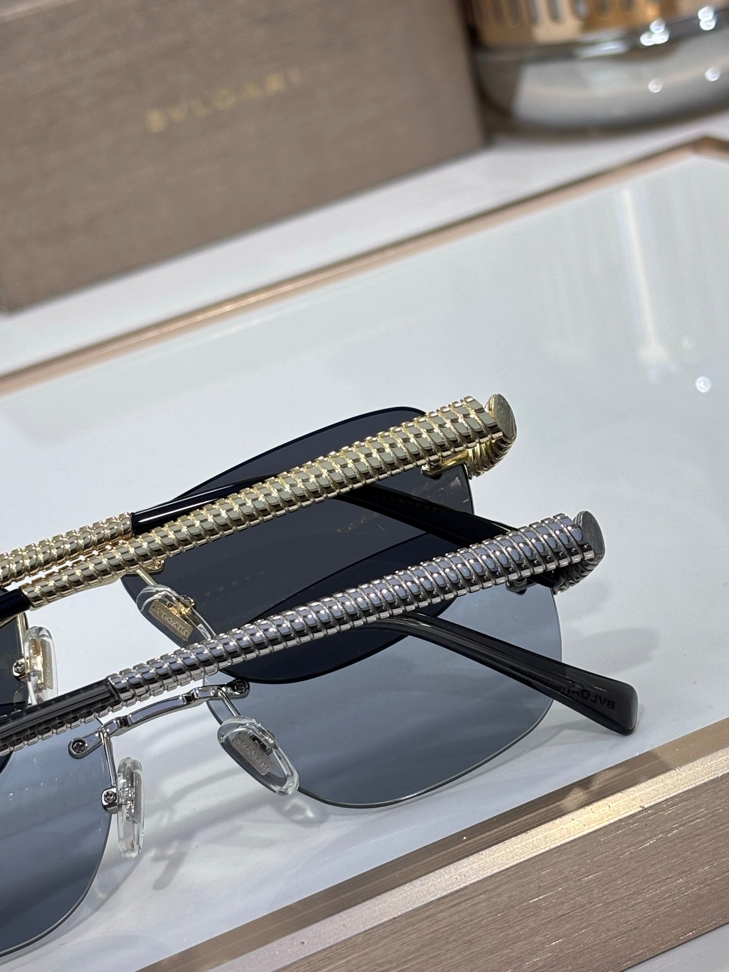 Pair of oval sunglasses on display with blue lenses and textured gold temple arms