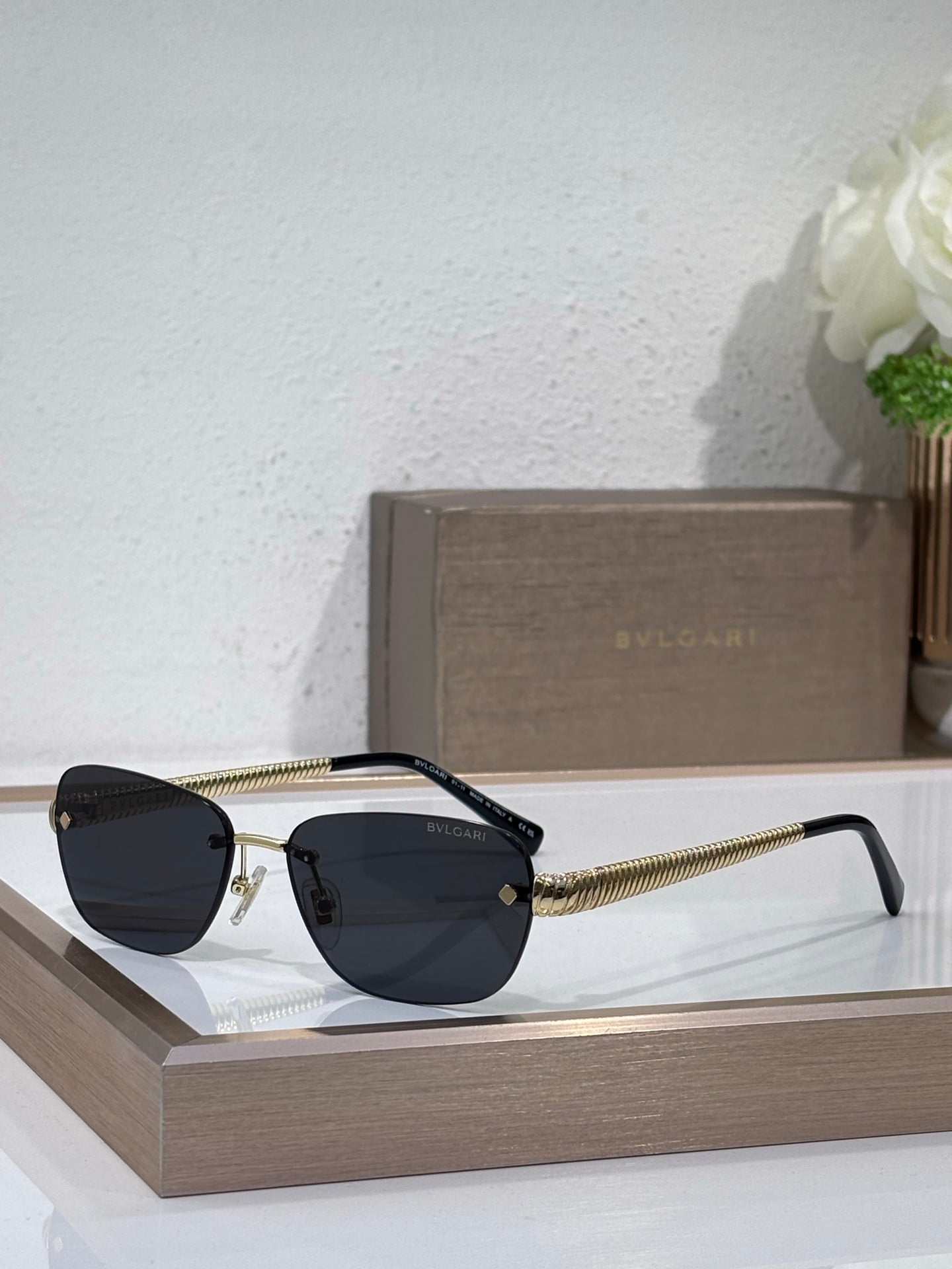 Metal-framed oval sunglasses with dark lenses and textured gold temple arms