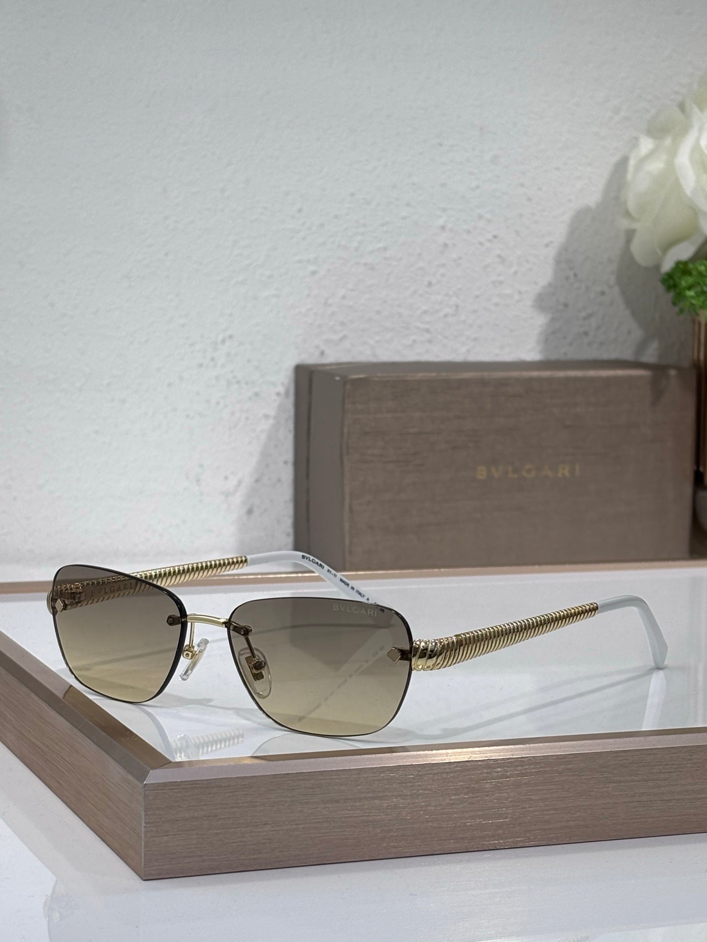 Metal-framed oval sunglasses with light-tinted lenses and textured gold temples