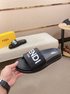 Black slide sandals with wide strap and large FENDI logo across the front.