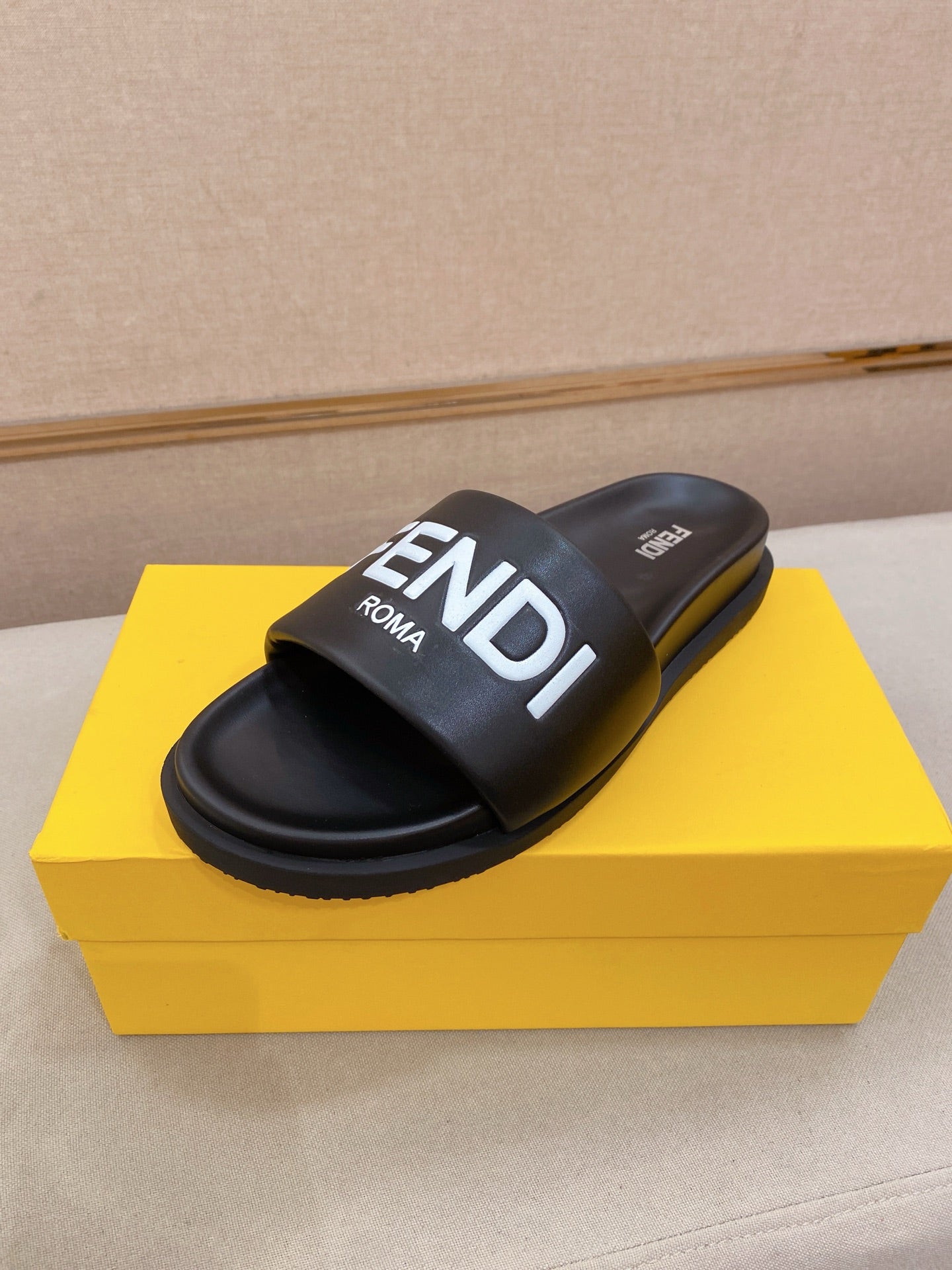 Black slide sandals with wide strap and FENDI logo on the upper.