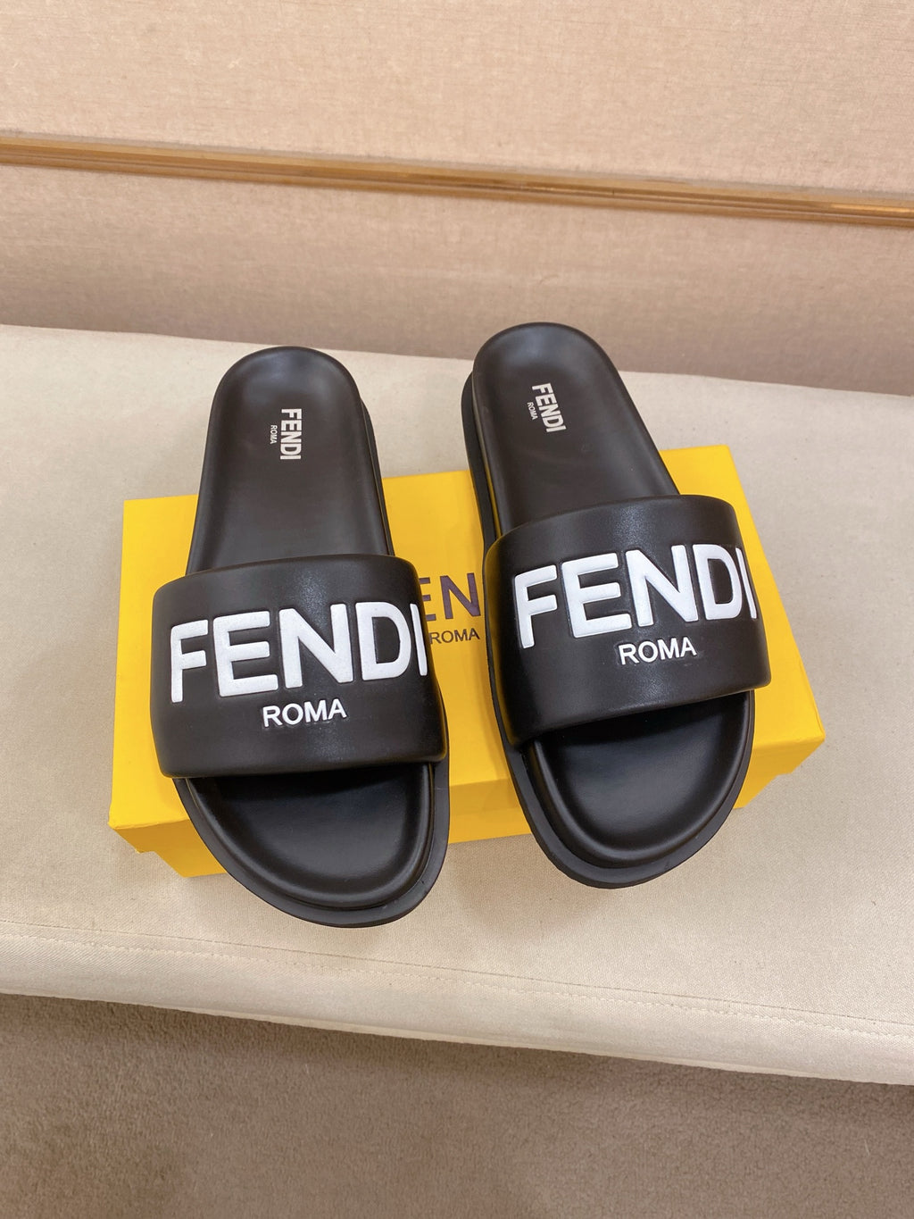 Pair of black slide sandals with wide strap and FENDI ROMA logo on the footbed.