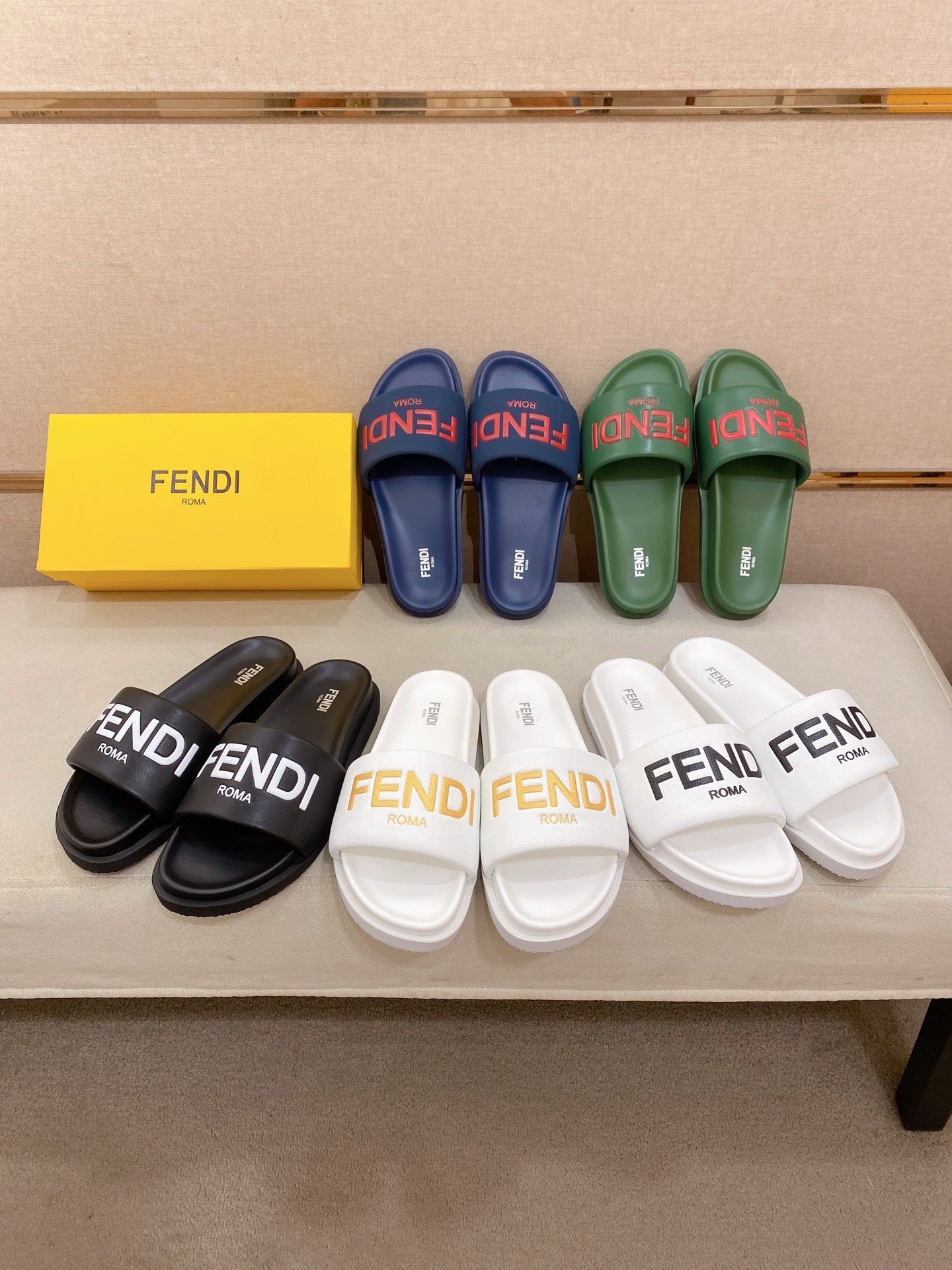 Assorted Fendi slide sandals in navy, green, black, and white on display.