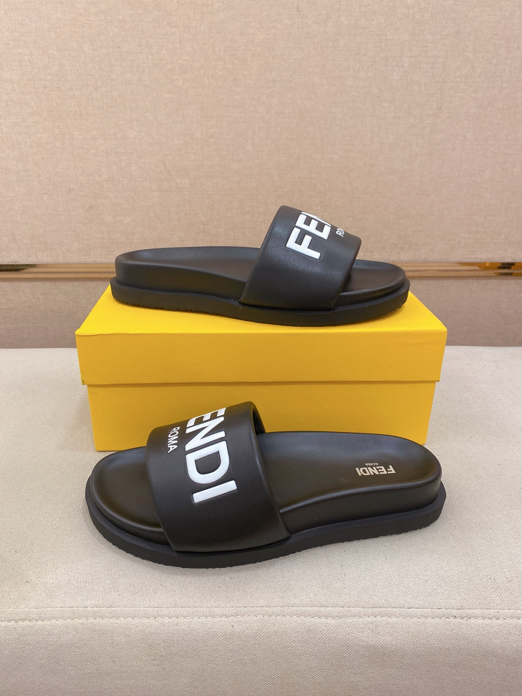 Black slip-on slide sandal with wide strap and raised FENDI logo patch on top.