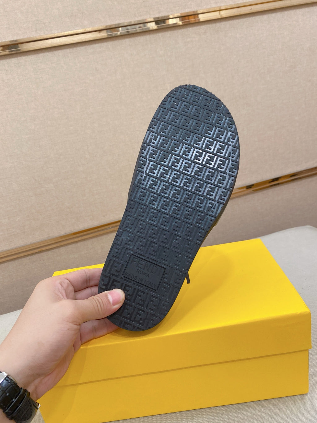 Bottom view of a dark slide sandal with repeating FENDI FF pattern grip sole.