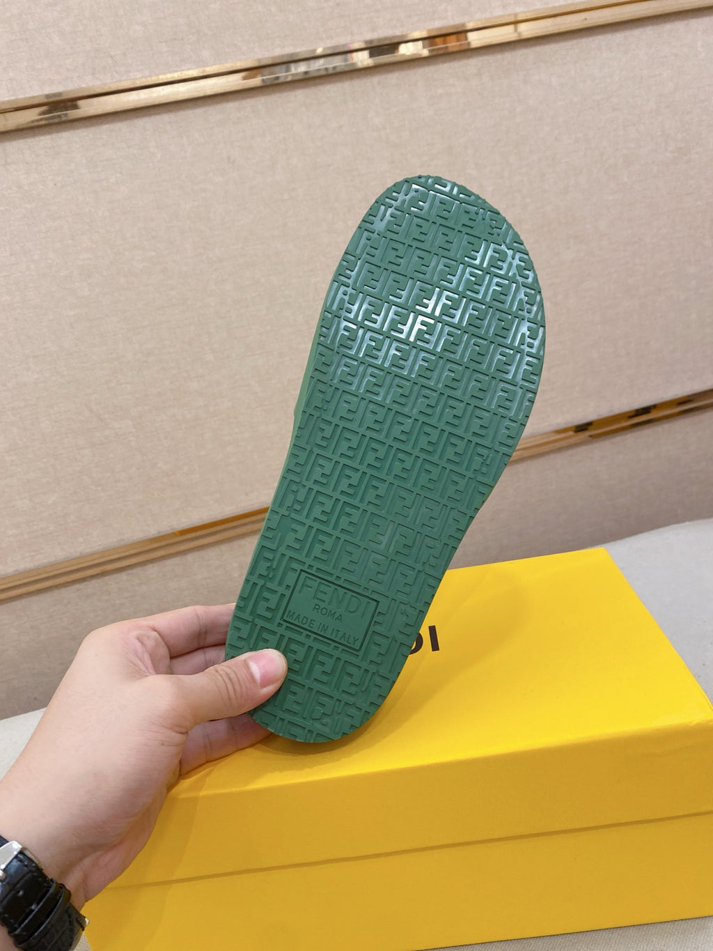 Green slide sandal outsole with textured pattern; underside held up in hand.