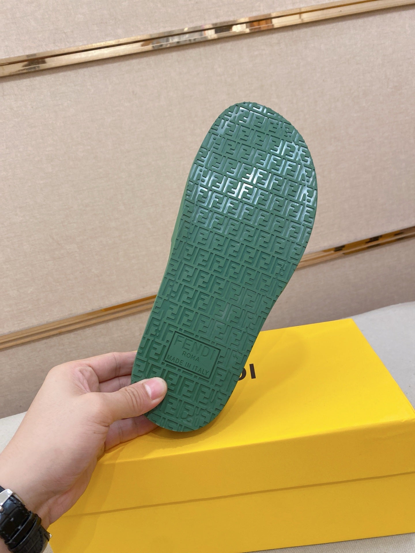 Green slide sandal outsole with textured pattern; underside held up in hand.