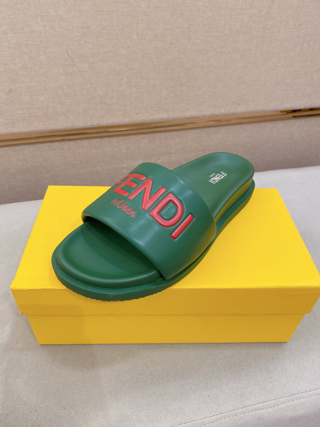 Green slide sandals with wide strap and large red FENDI logo on the footbed.