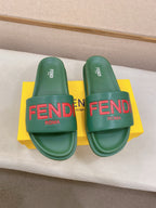 Two green FENDI slide sandals with red FENDI logo on the front straps.