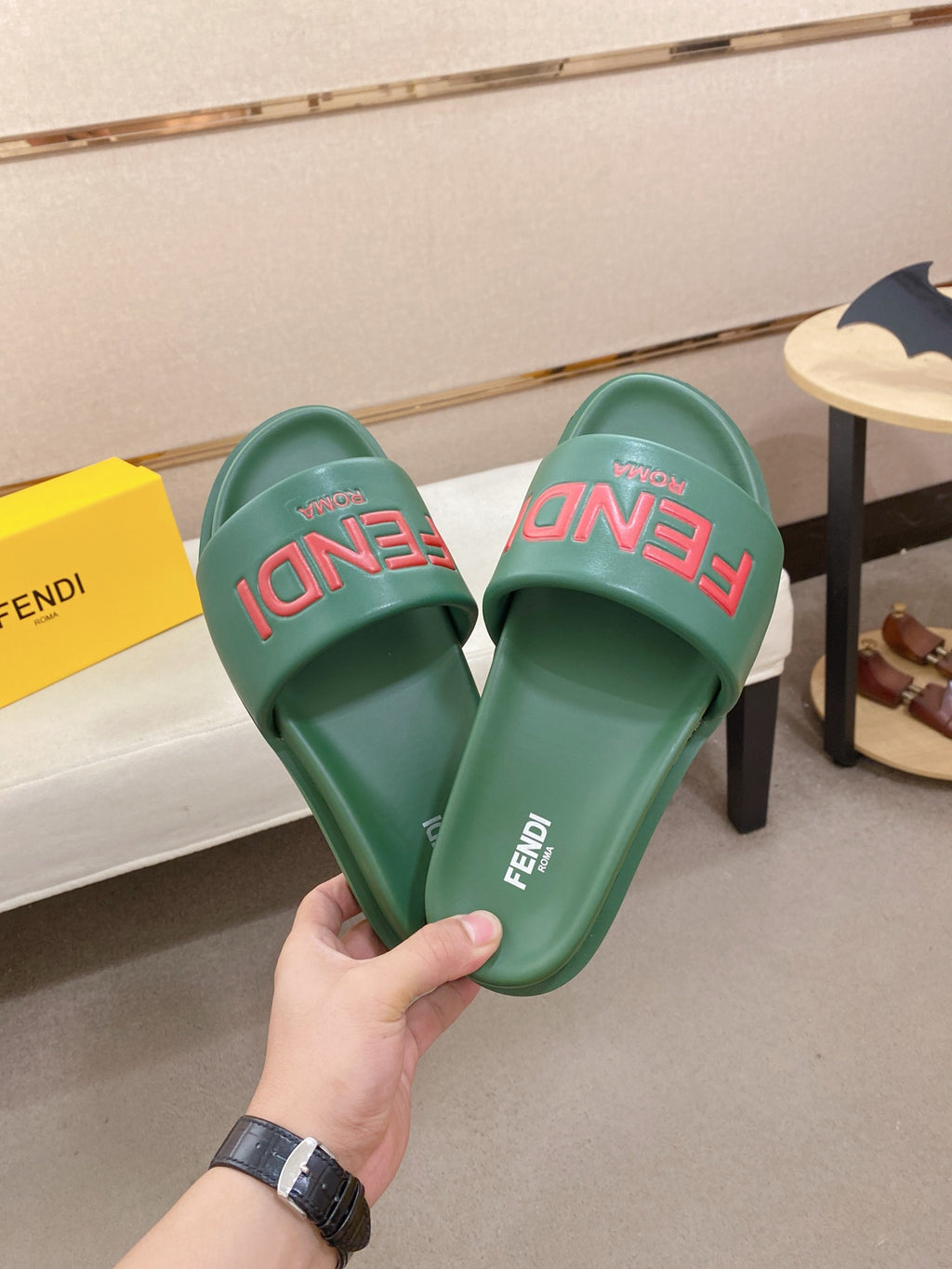 Pair of green slide sandals showing red FENDI logo on the straps and footbeds.