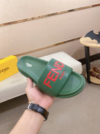 Green slide sandal on a box, with red FENDI logo on the strap and footbed.