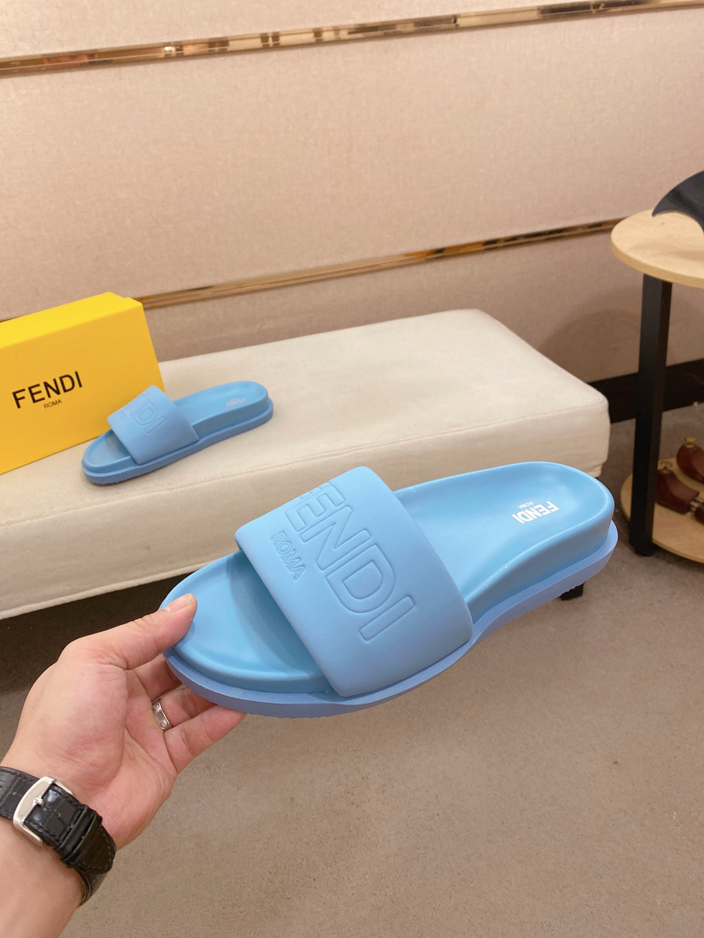 Light blue slide sandals on bench with embossed logo on the wide strap and footbed