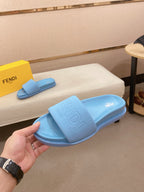 Light blue slide sandals on bench with embossed logo on the wide strap and footbed