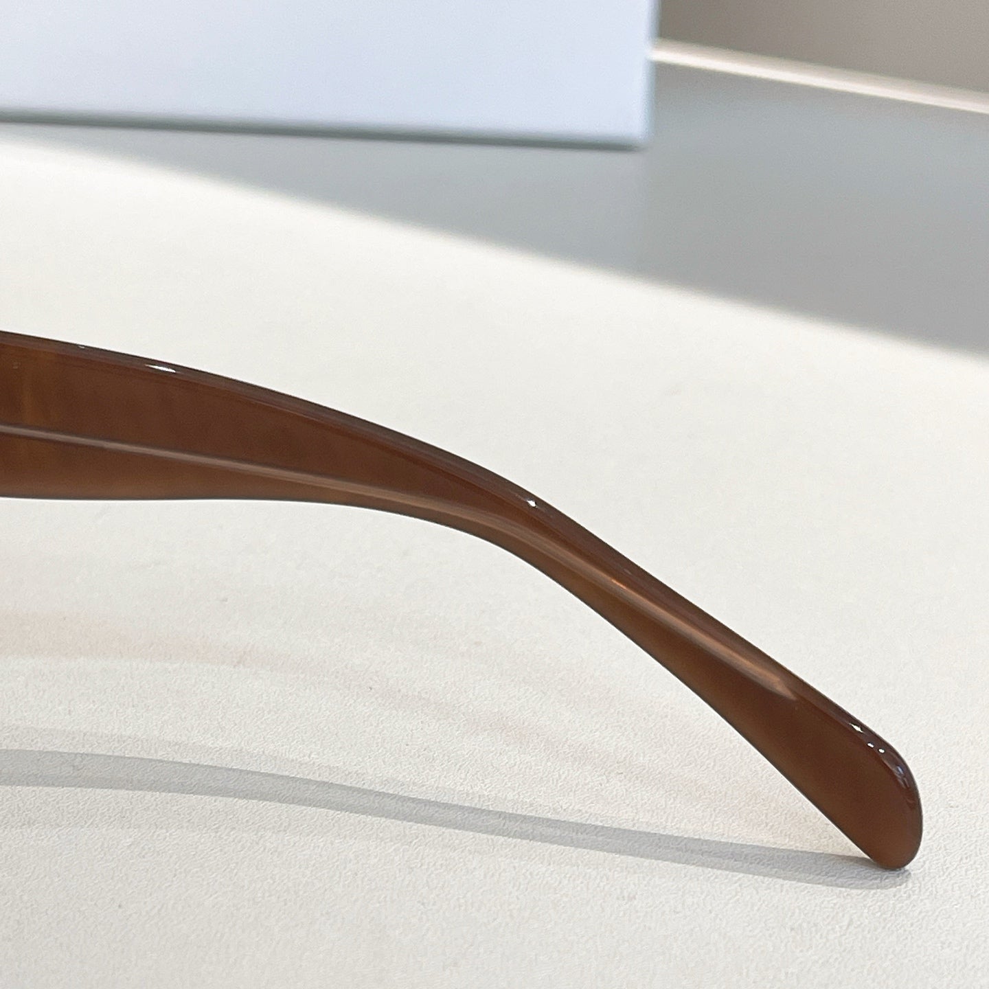 Brown eyeglass temple with curved end and glossy finish