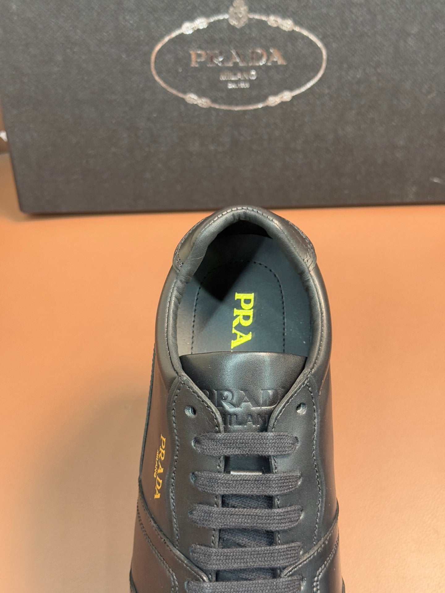 Dark leather sneaker interior with Prada logo on the tongue.