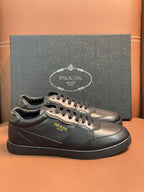 Dark leather low-top sneakers with Prada emblem and lace-up front.