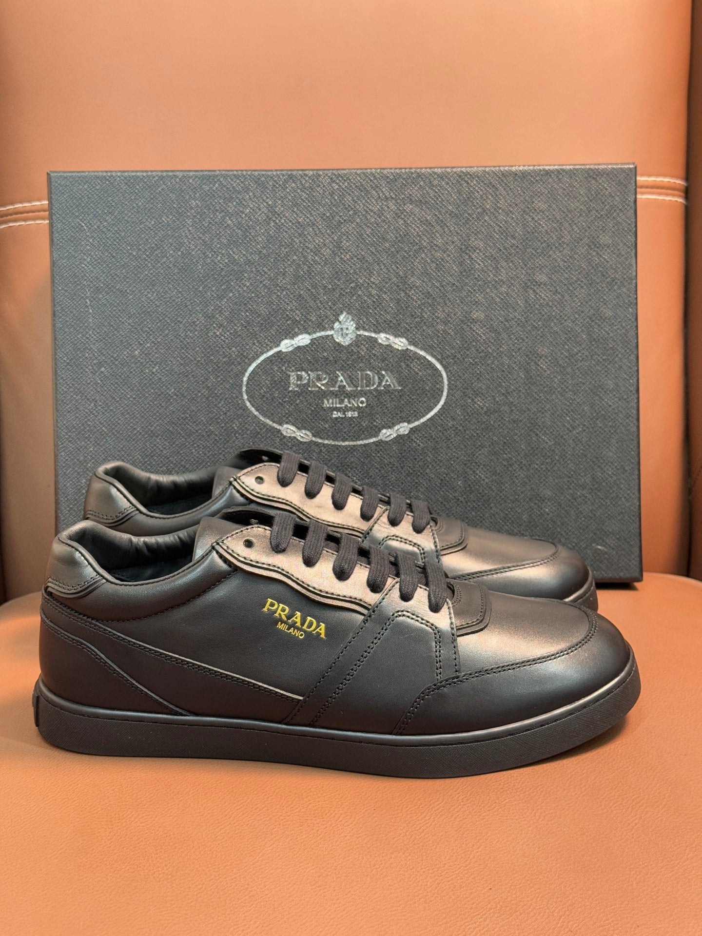 Dark leather low-top sneakers with Prada emblem and lace-up front.