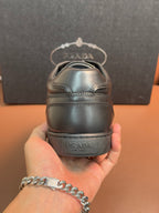 Dark leather sneaker heel with Prada branding and rear stitching.