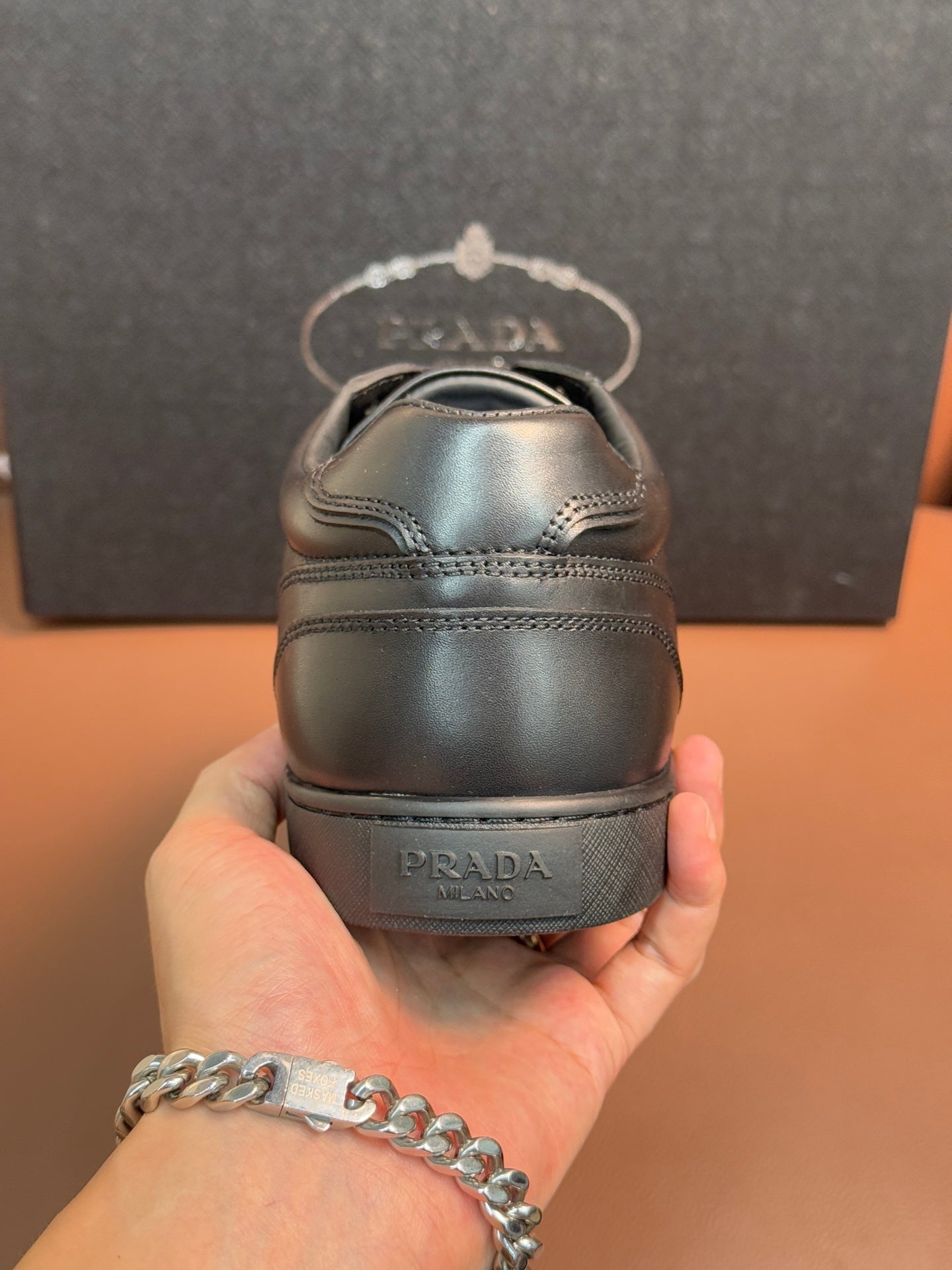 Dark leather sneaker heel with Prada branding and rear stitching.