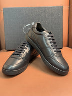 Dark leather lace-up sneakers with metal eyelets and stitched panels.