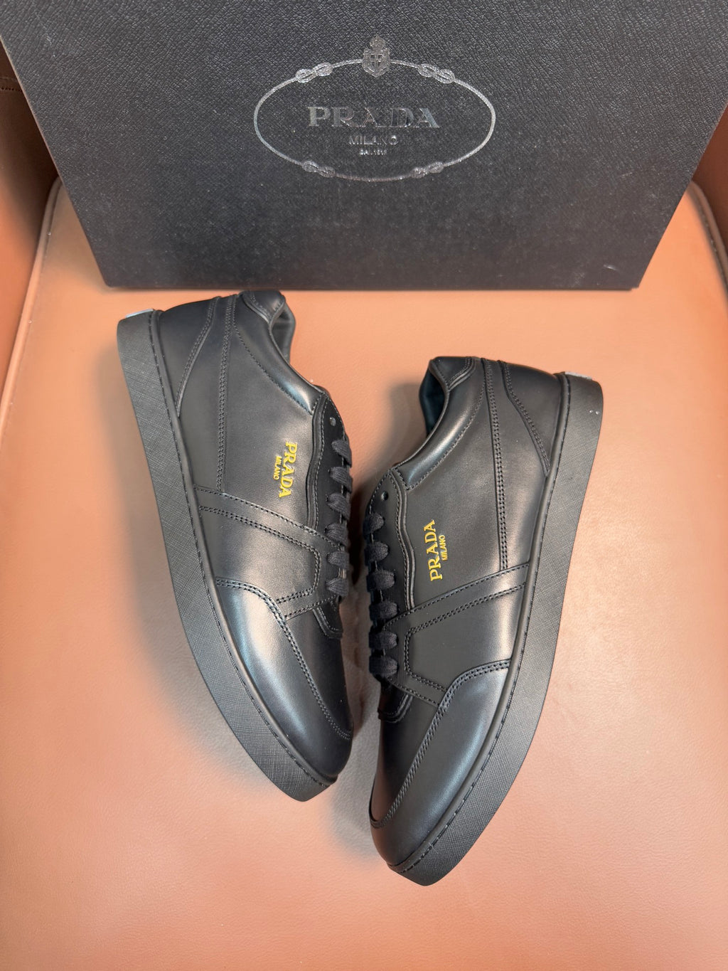 Dark leather low-top sneakers with lace closure and Prada side logo.