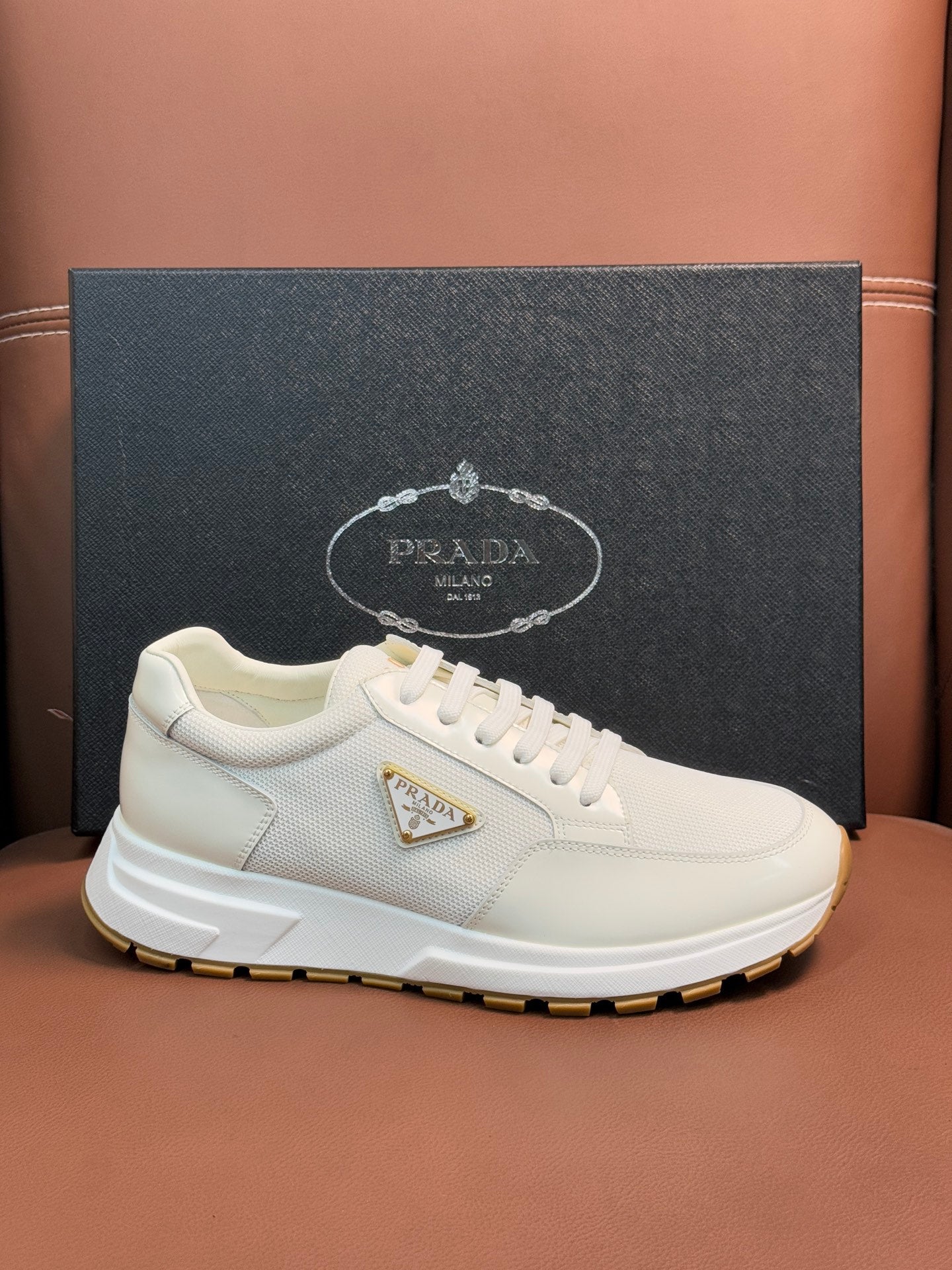 Prada unisex white sneakers, front side view with triangle logo on textured upper