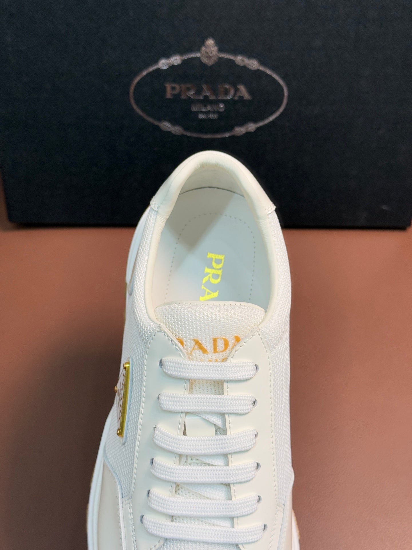 Prada unisex white sneakers, close-up of lace-up vamp with triangle logo
