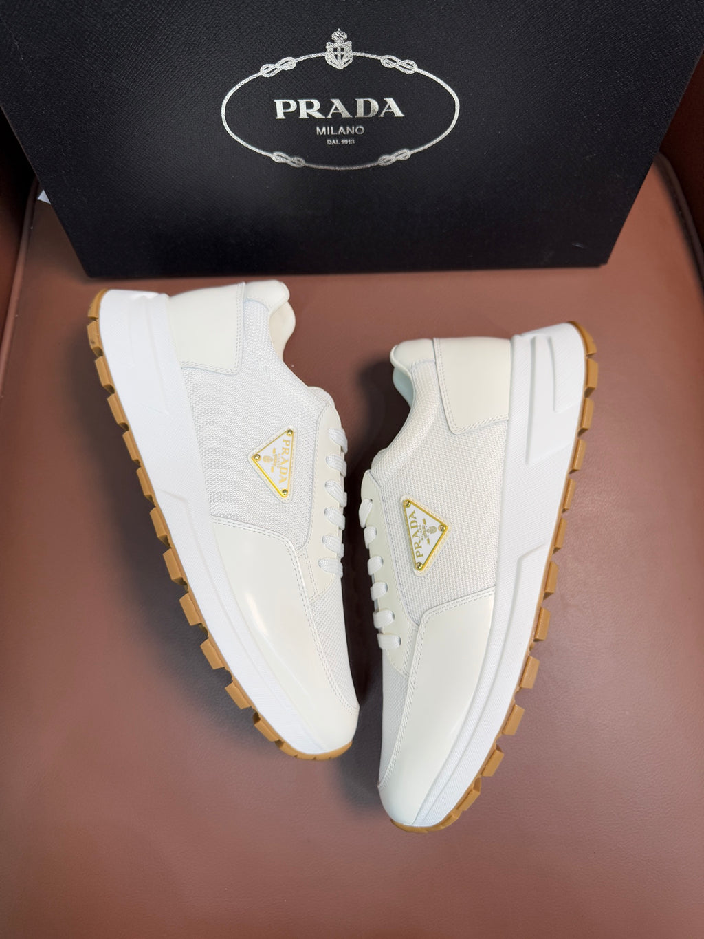 Prada unisex white sneakers, side view showing triangle logo and gum sole