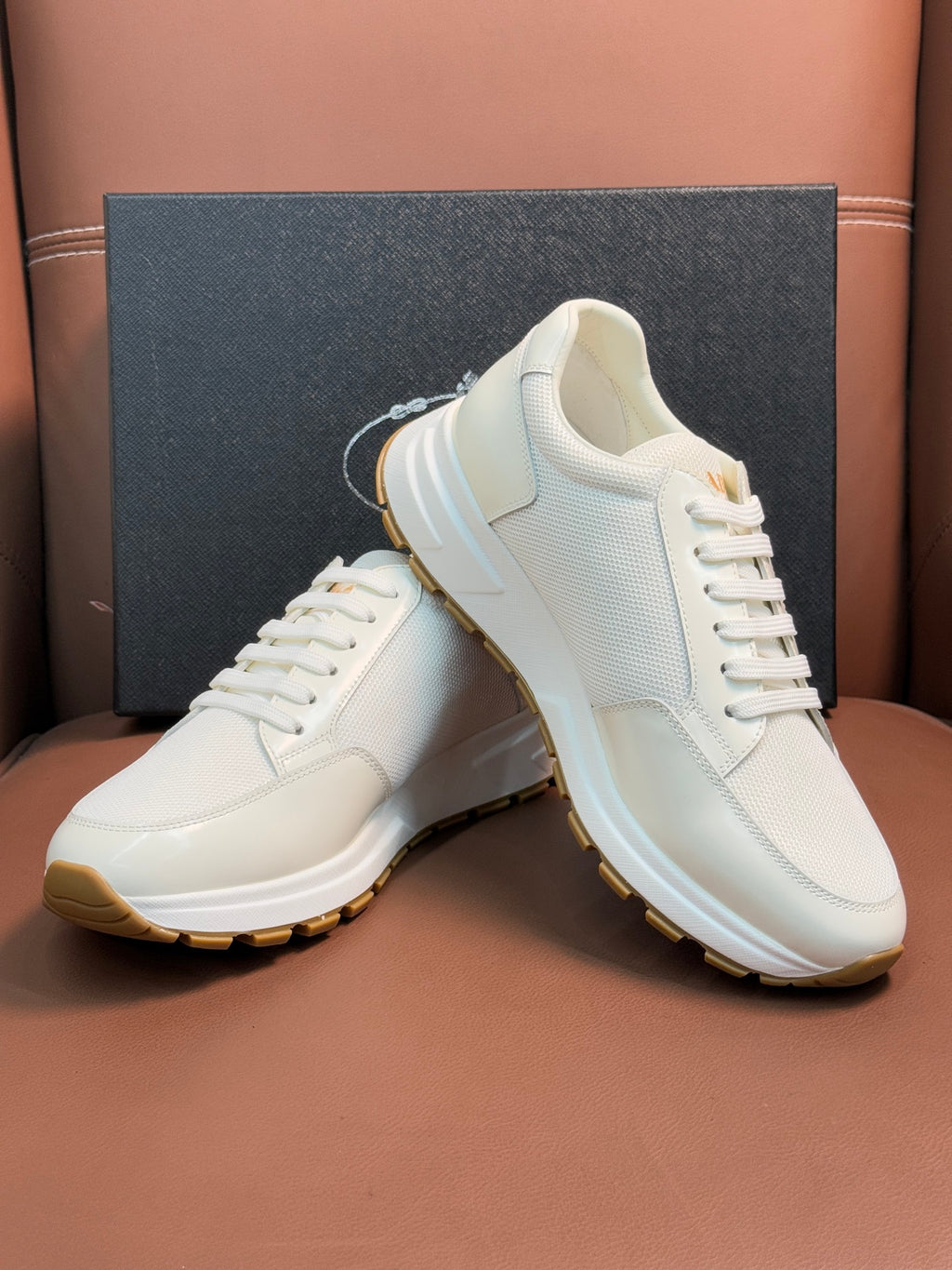 Prada unisex white sneakers, angled view of leather upper and gum sole