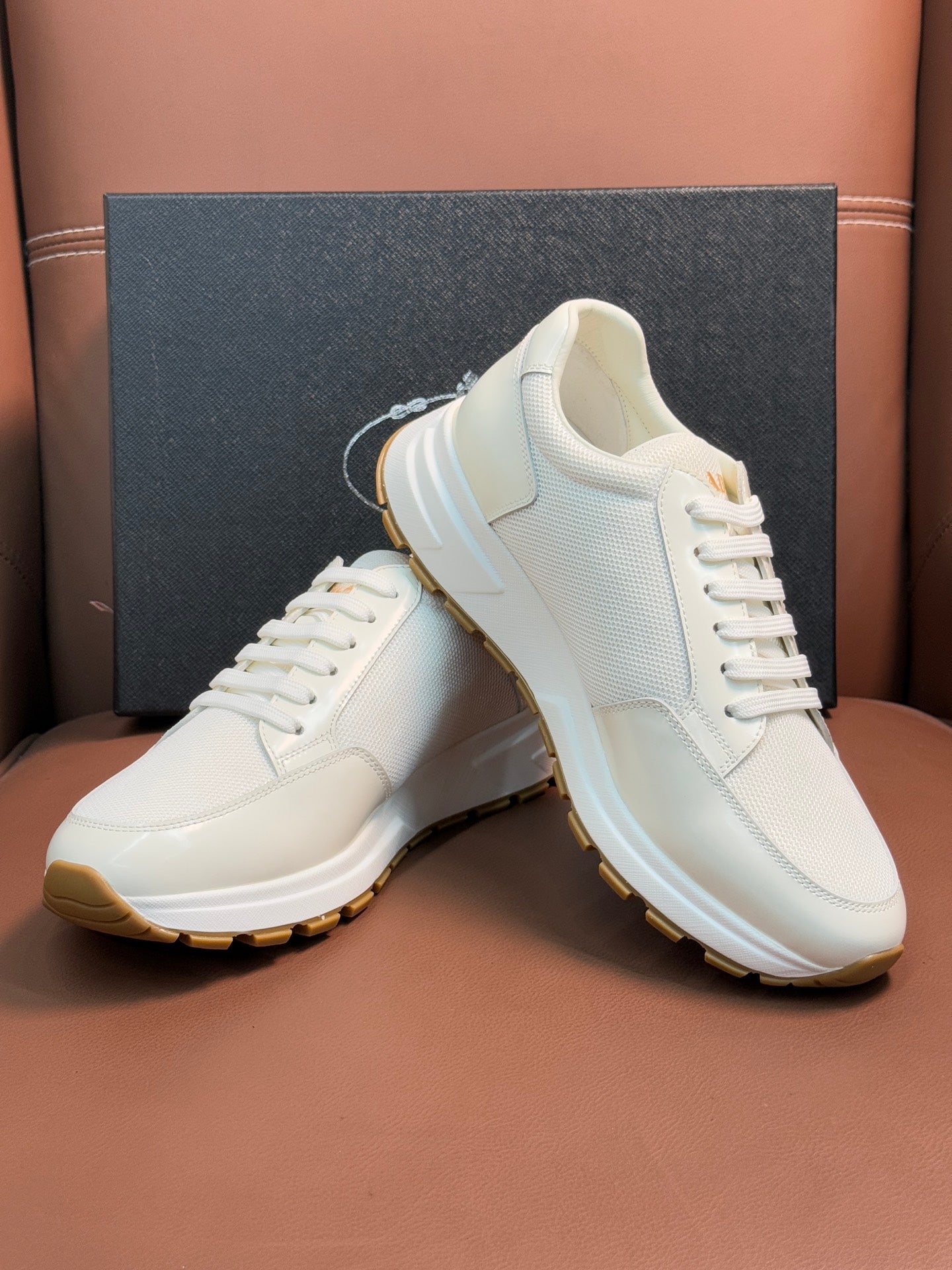 Prada unisex white sneakers, angled view of leather upper and gum sole
