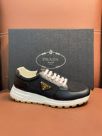Prada unisex sneakers, dark upper, white laces, beige collar lining, yellow outsole.